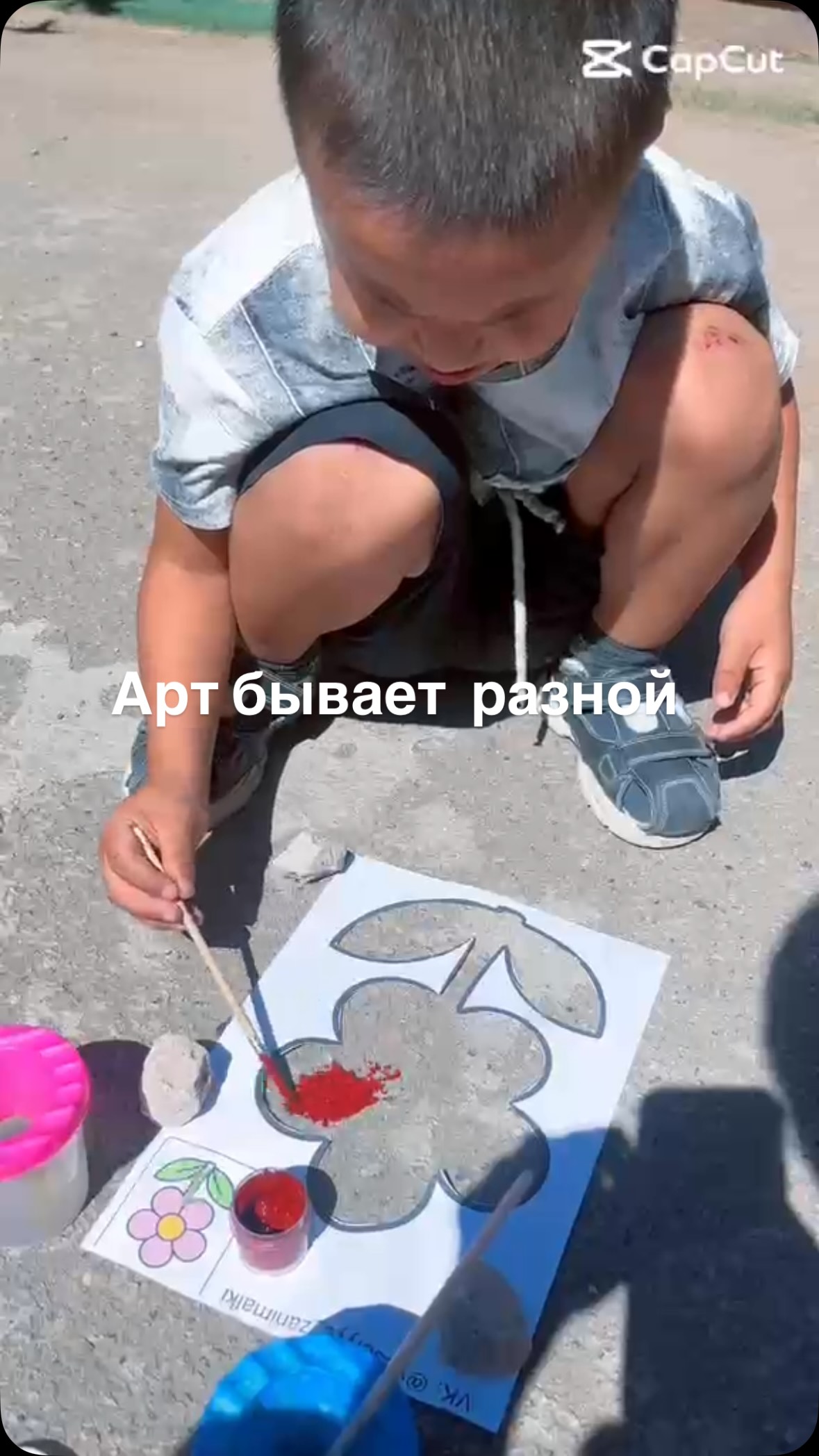 Аулада гүл суретін бояп отырған бала